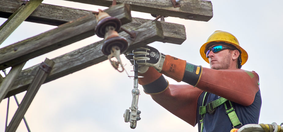 A Consumers Energy lineworker who is performing scheduled outage work on a pole